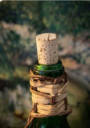Green wine bottle with a cork stopper and woven raffia wrap